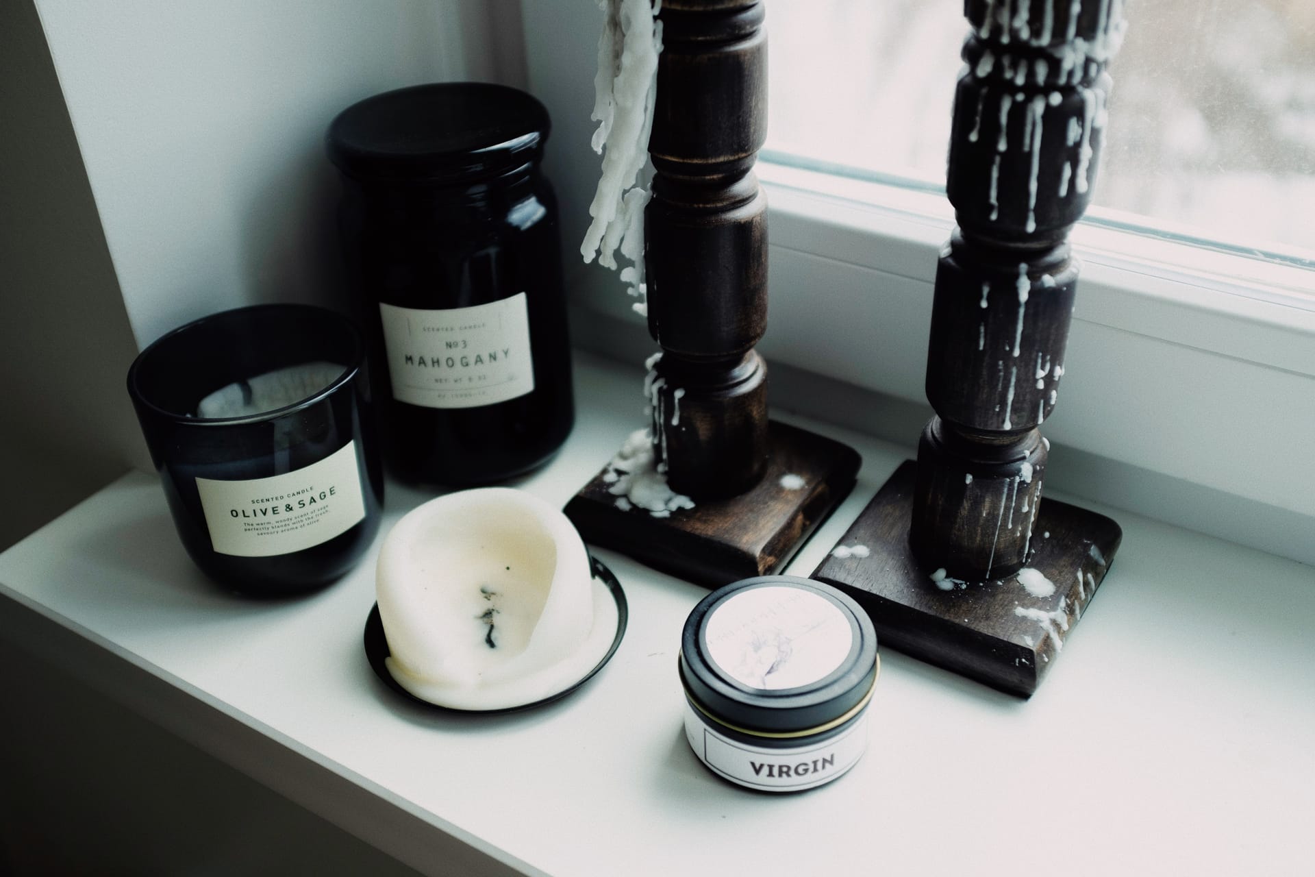Candles in glass jars arranged on a windowsill