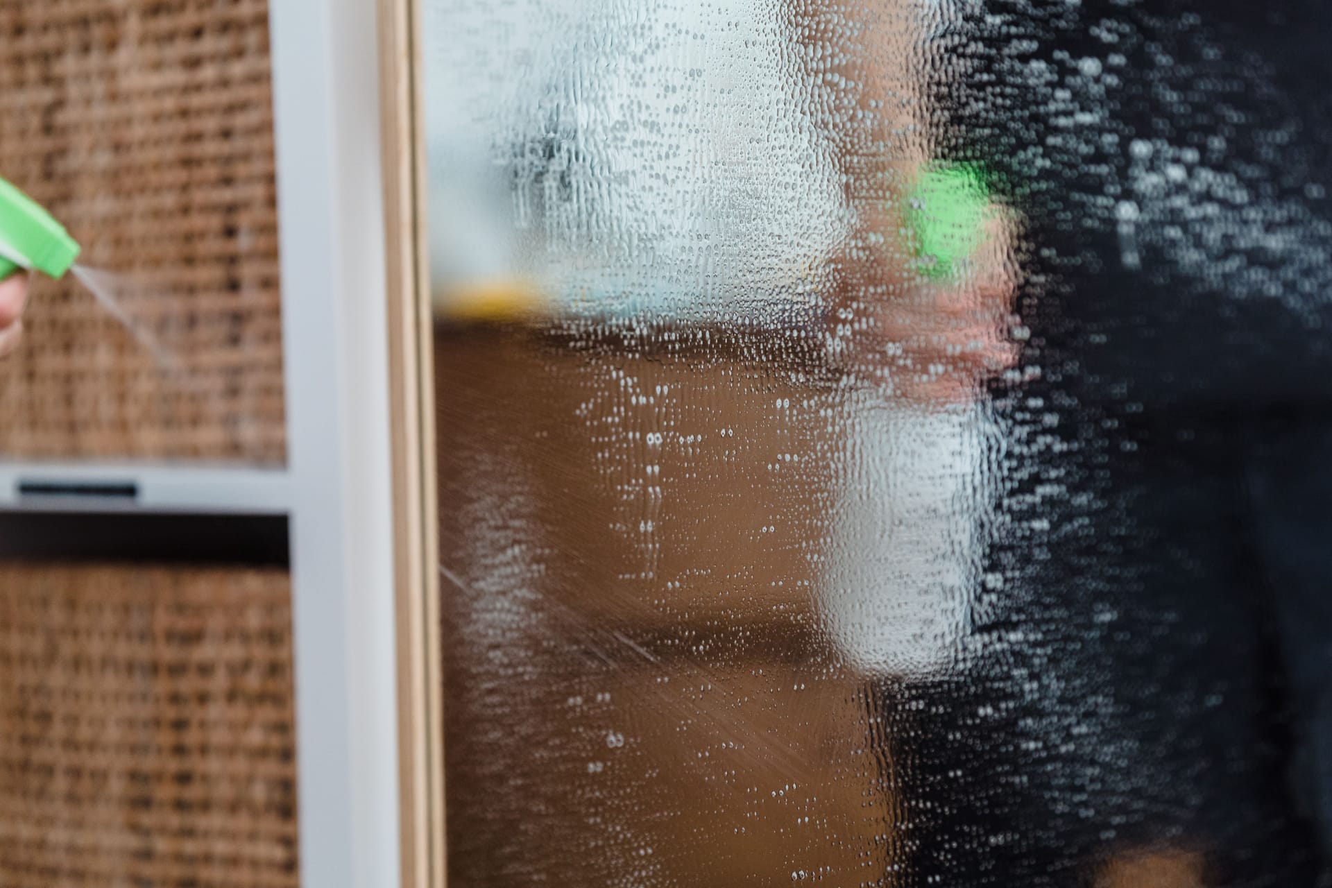 Cleaning a mirror with a spray bottle indoors