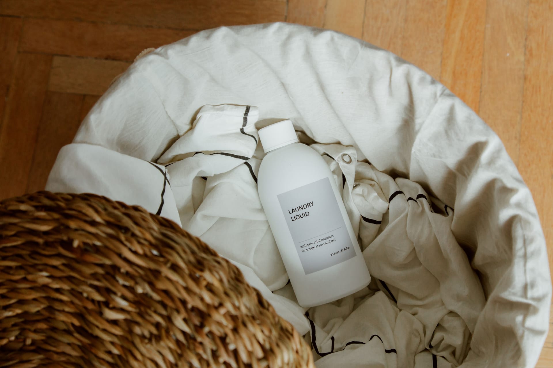 A bottle of laundry liquid in a basket of white linens