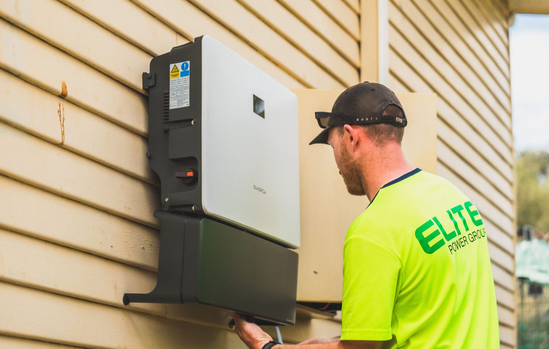 An installer fitting a wall-mounted battery inverter