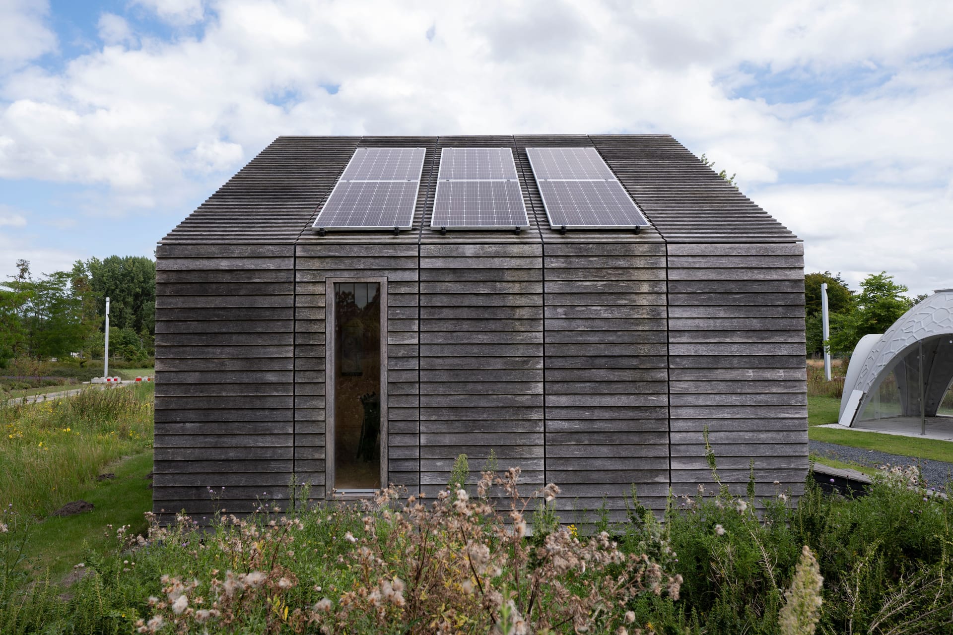 An off-grid timber building with solar panels and a polytunnel