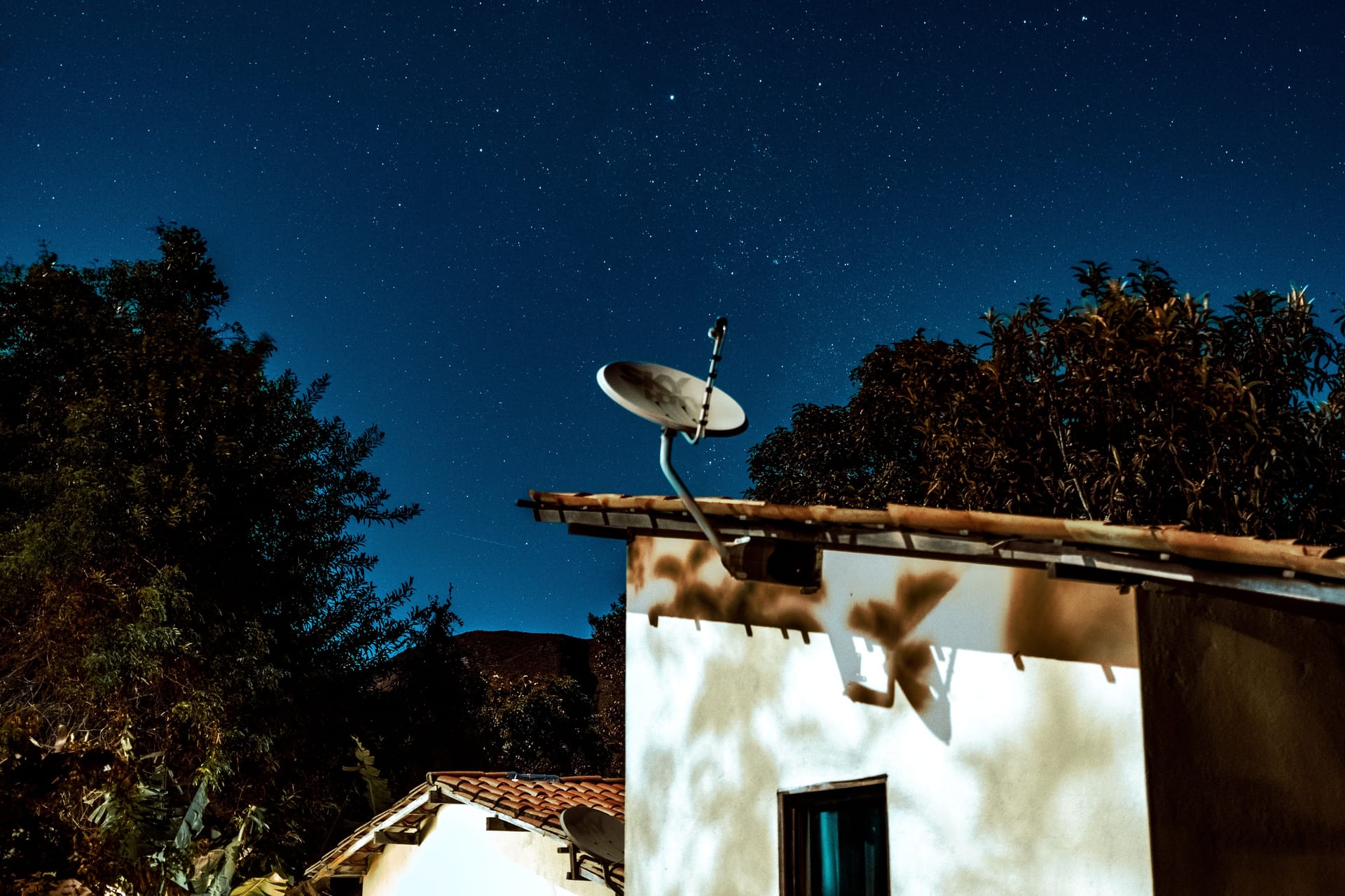 A satellite dish on a rural house at night