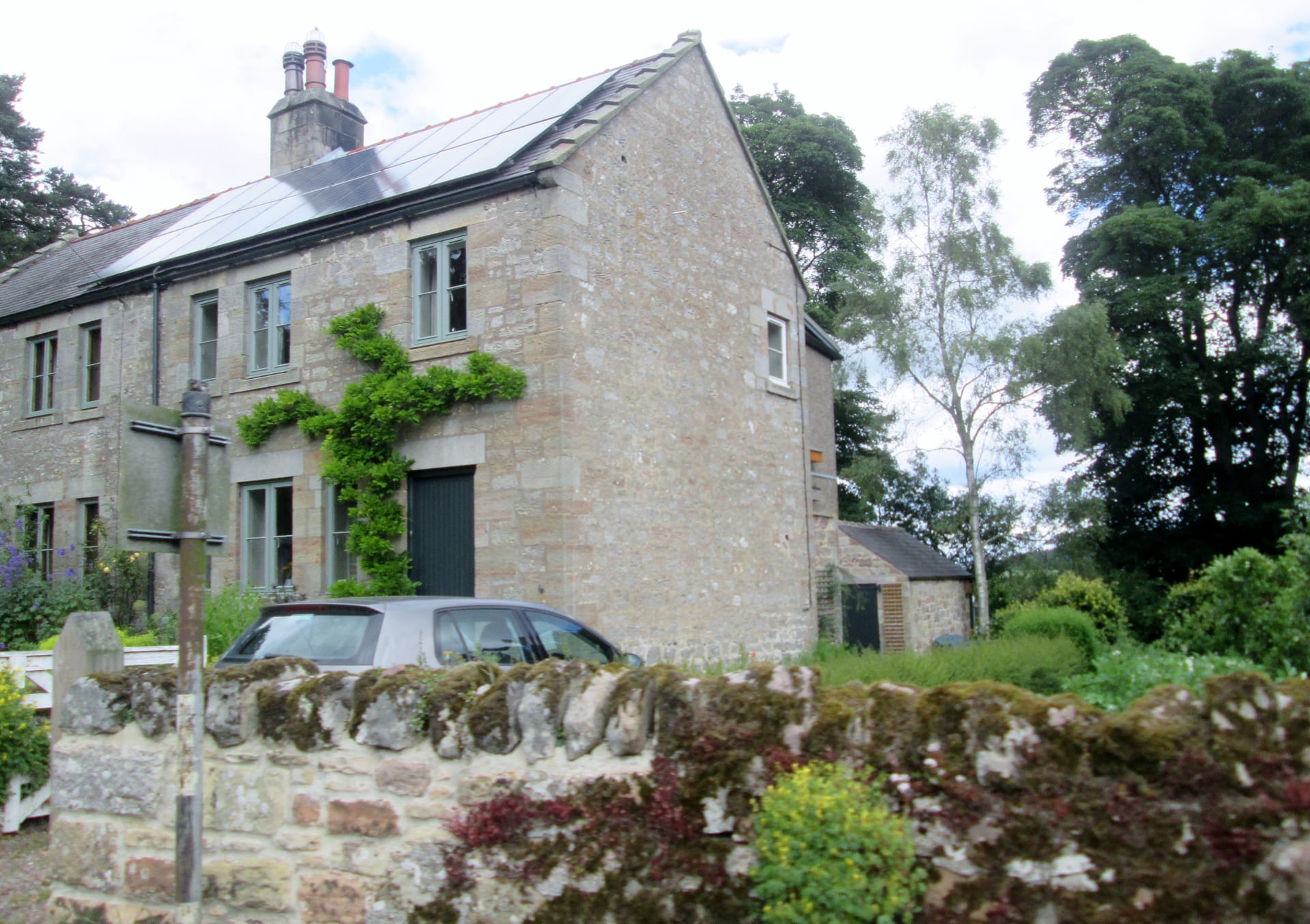 A stone cottage with roof-mounted solar panels