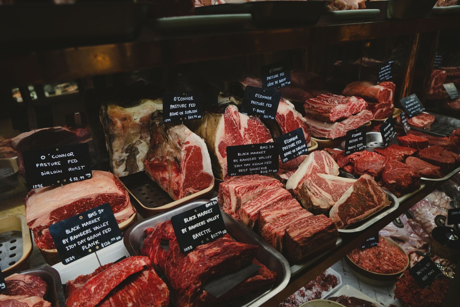 A butcher's counter with cuts of meat and price cards